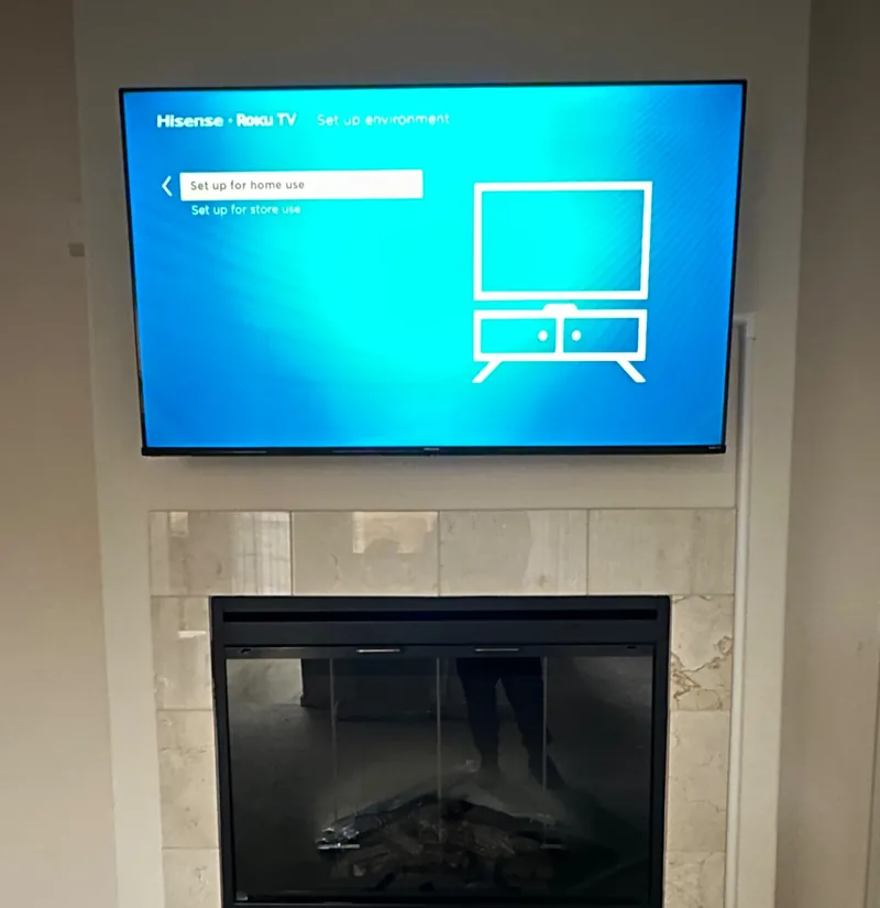 75-inch Hisense TV mounted above a fireplace in Seaside with external cable concealment